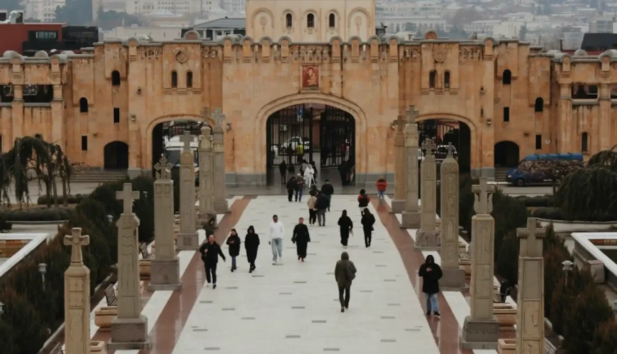 Grand entrance to the Holy Trinity Cathedral (Sameba) in Tbilisi, with a long pathway leading to the main gates and a central dome in the background.