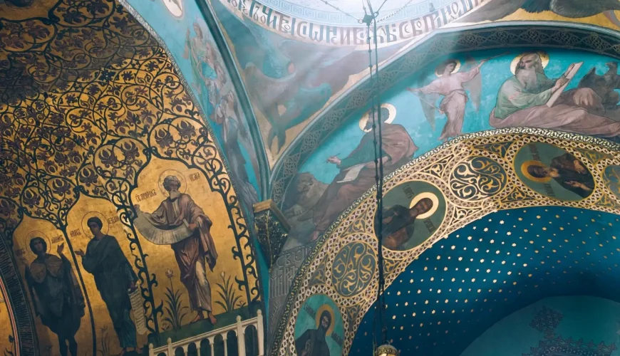 Close-up of the ornate and colorful murals inside the Sioni Cathedral in Tbilisi, featuring religious figures and intricate gold leaf patterns on the walls and dome.