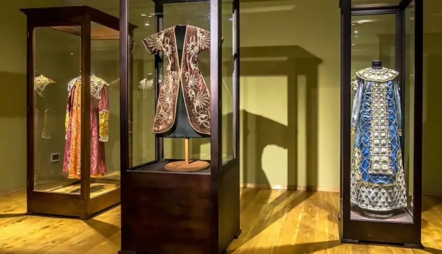 An exhibition room at the Art Palace of Georgia (Museum of Cultural History) in Tbilisi, showcasing richly embroidered historical costumes and garments displayed in glass cases