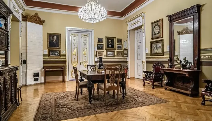 A beautifully furnished room at the Art Palace of Georgia (Museum of Cultural History) in Tbilisi, with a central dining table, elegant chairs, a crystal chandelier, and walls adorned with framed artworks and portraits.