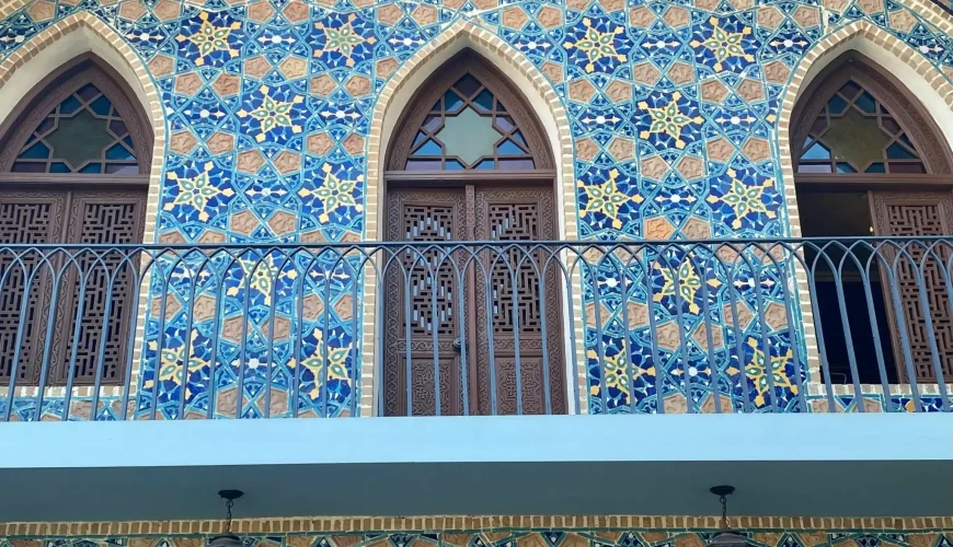Colorful and ornate blue and yellow tiled facade of the Chreli Abano (Orbeliani) sulfur bathhouse in Tbilisi, with a balcony and arched windows.
