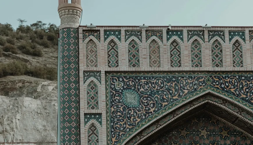 Close-up of the ornately tiled facade and minaret of the Tbilisi Juma Mosque, showcasing intricate blue, green, and brown patterns and arches