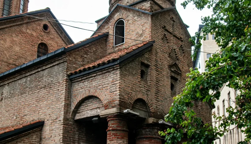 Close-up of an old brick church in Tbilisi Old Town with a distinctive bell tower, arched entrances, and traditional Georgian architecture.
