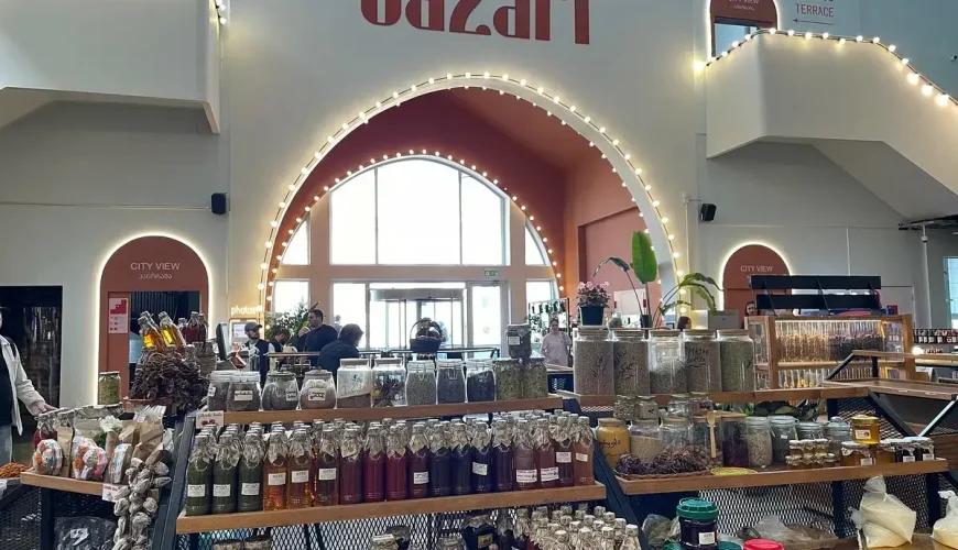 A stall with a variety of local products, including bottled sauces, spices in jars, and cheeses, at Bazari Orbeliani in Tbilisi