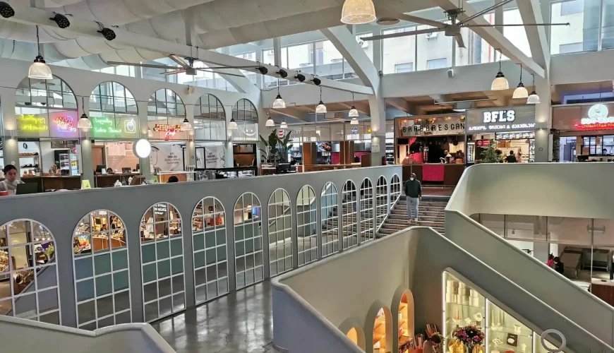 A bright and modern interior of Bazari Orbeliani with multiple food stalls and a wide staircase in the foreground