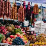 A close-up of a market stall at Dezerteer Bazaar, with strings of churchkhela hanging above fresh fruit and vegetables