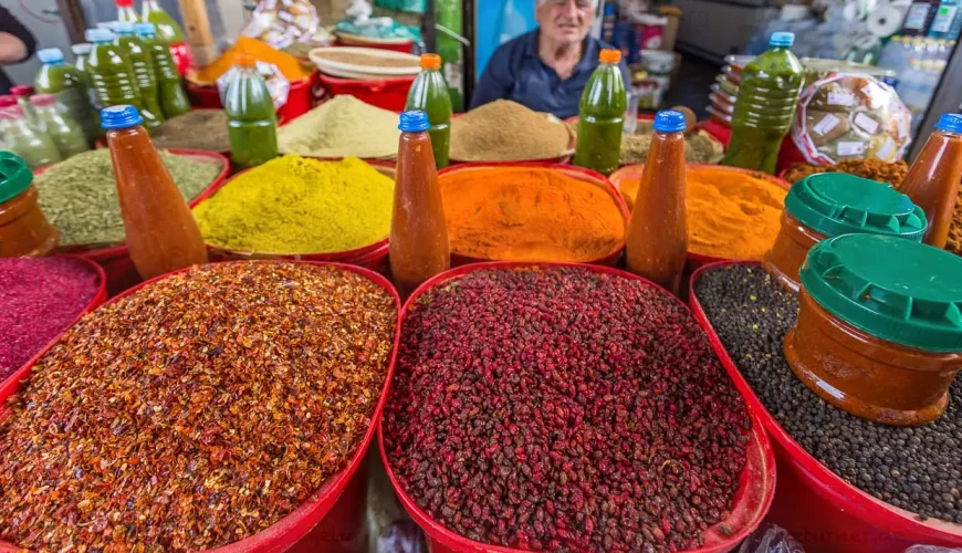 A vendor at Dezerteer Bazaar standing behind large bowls of colorful Georgian spices and chili sauces