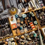 A detailed close-up of a vendor's table at Dry Bridge Flea Market, showing a variety of vintage medals, silverware, and small antiques