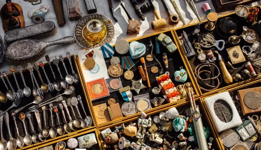 A detailed close-up of a vendor's table at Dry Bridge Flea Market, showing a variety of vintage medals, silverware, and small antiques