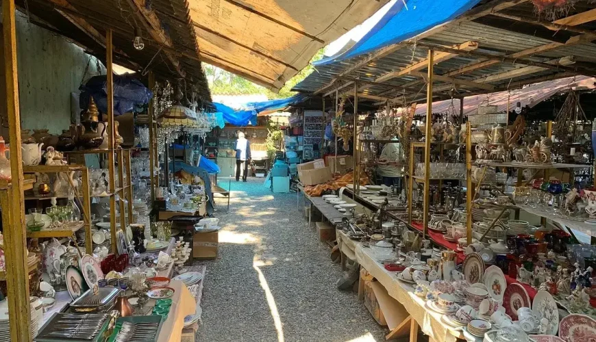 A long aisle of stalls at Dry Bridge Flea Market in Tbilisi, with vendors selling antiques, pottery, and various vintage goods under makeshift roofs