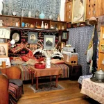 A richly decorated room inside the Elene Akhvlediani Museum in Tbilisi, Georgia, filled with personal belongings, artworks, traditional textiles, and antique furnishings, reflecting the artist's eclectic style.