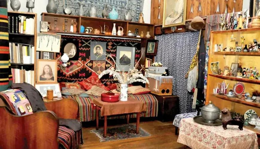 A richly decorated room inside the Elene Akhvlediani Museum in Tbilisi, Georgia, filled with personal belongings, artworks, traditional textiles, and antique furnishings, reflecting the artist's eclectic style.