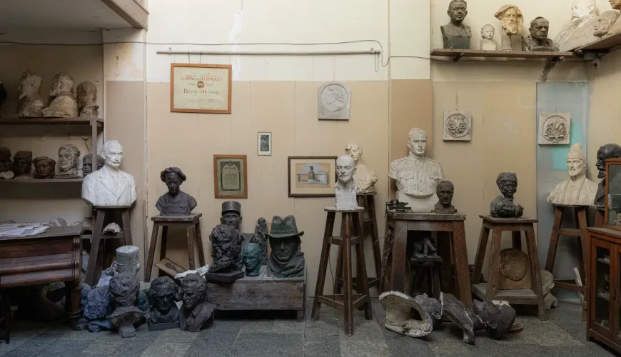 An interior view of the Iakob Nikoladze Museum in Tbilisi, Georgia, showcasing a collection of plaster and bronze busts, sculptures, and various art tools, resembling an artist's studio.