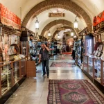 A long, arched hallway of an underground bazaar in Tbilisi, with display cases full of jewelry, art, and traditional goods