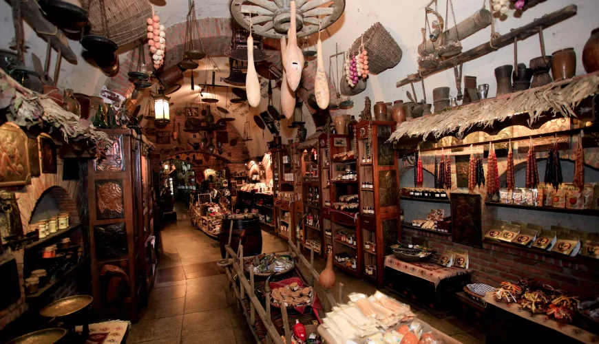 A warmly lit underground souvenir shop in Meidan Bazaar, Tbilisi, filled with traditional Georgian products and crafts, including hanging sausages and churchkhela