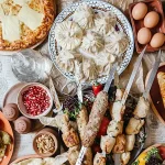 A lavish spread of traditional Georgian dishes on a table, including Khachapuri, Khinkali, Mtsvadi kebabs, fresh vegetables, cheese, and bread, likely from the Museum of Culinary Recipes in Tbilisi.