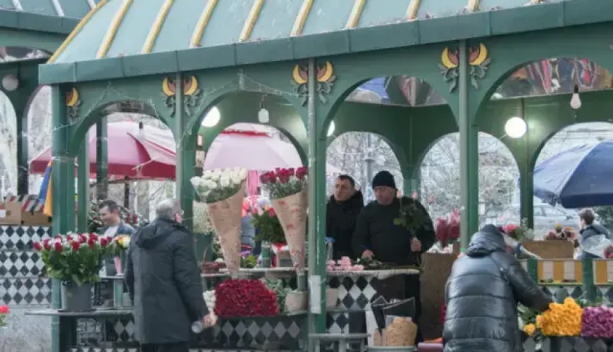 Flower vendors at Orbeliani Flower Market in Tbilisi under a green-domed structure, with bouquets of roses and other flowers on display