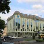 The impressive exterior of the Shalva Amiranashvili Museum of Fine Arts in Tbilisi, Georgia, showcasing its distinctive light-colored facade with numerous tall arched windows, facing a busy street.