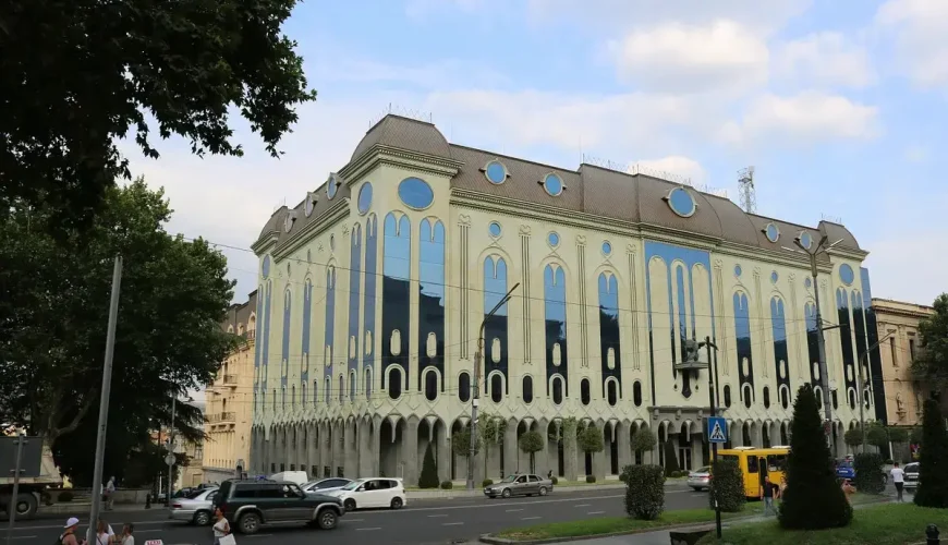 The impressive exterior of the Shalva Amiranashvili Museum of Fine Arts in Tbilisi, Georgia, showcasing its distinctive light-colored facade with numerous tall arched windows, facing a busy street.