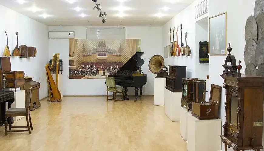 Inside the State Museum of Georgian Folk Songs and Musical Instruments in Tbilisi, Georgia, showcasing a diverse collection of historic instruments including a grand piano, harp, gramophone, and traditional Georgian folk instruments.